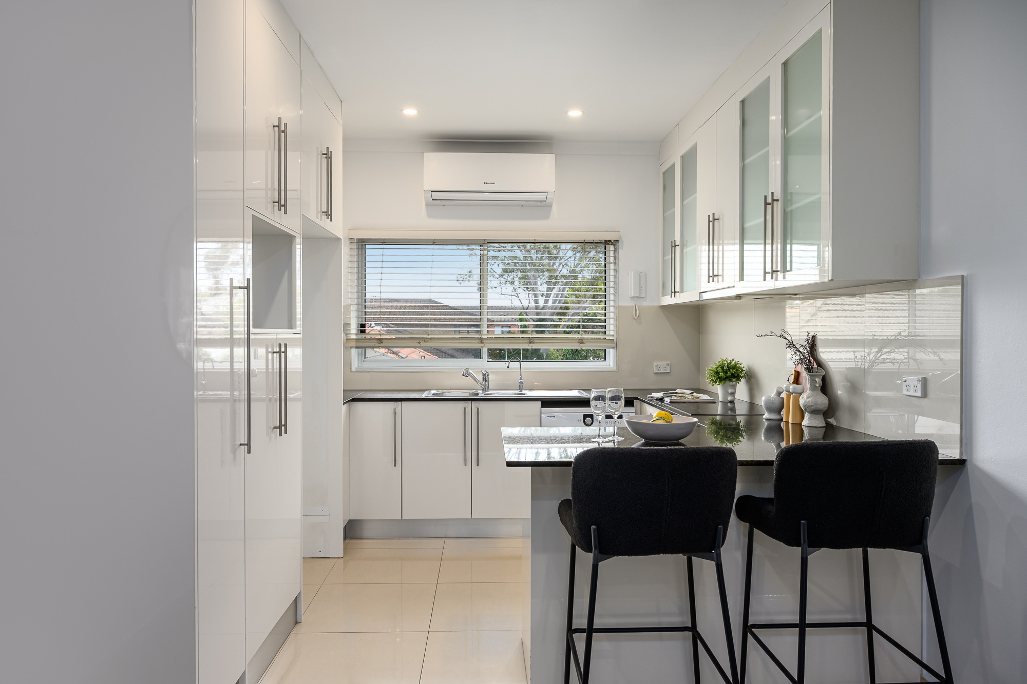 White kitchen with stone benchtop, breakfast bar and window